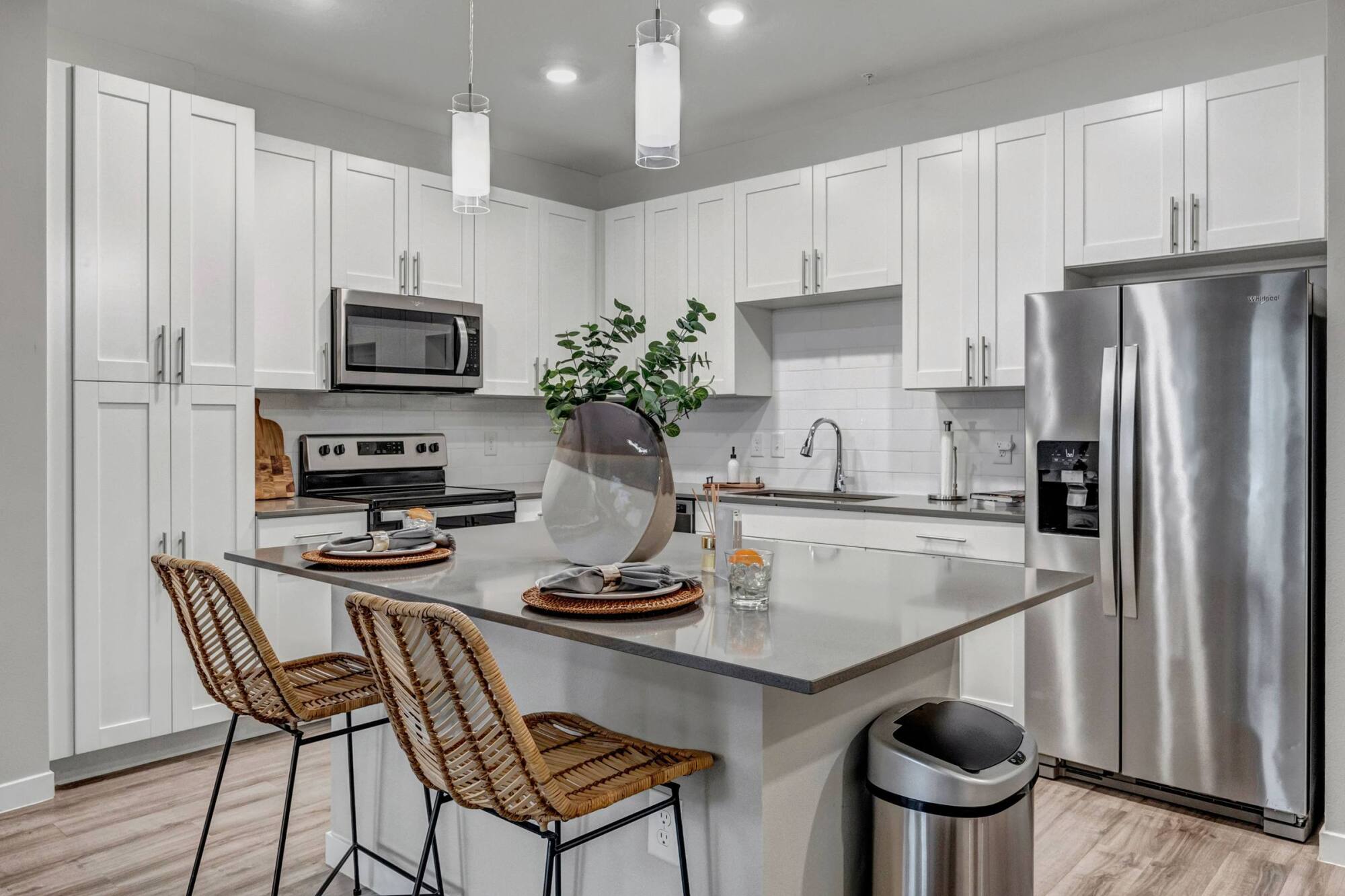 Modern kitchen with white cabinets, stainless steel appliances, island seating, and decorative accents.